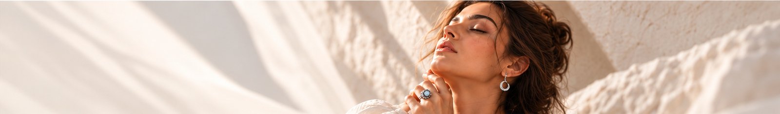 Woman in silver crescent jewellery, resting in warm light